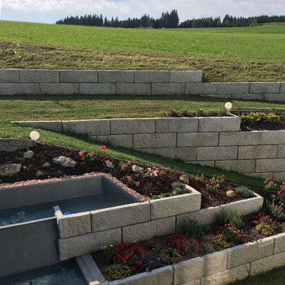 Mehrstufige Gartenlösung aus Beton – ideal zur Hangbefestigung mit Blumenbeet und Beleuchtung