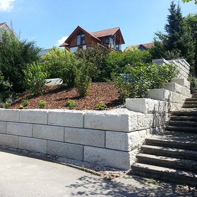 Helle Betonsteine stützen den Hang und schließen sauber an den Treppenaufgang an